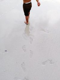 Low section of man walking on beach