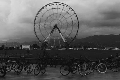 Ferris wheel in city against cloudy sky