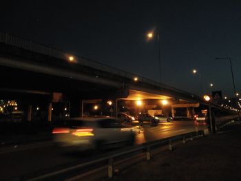 Illuminated city street against sky at night