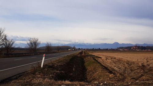 Road amidst field against sky