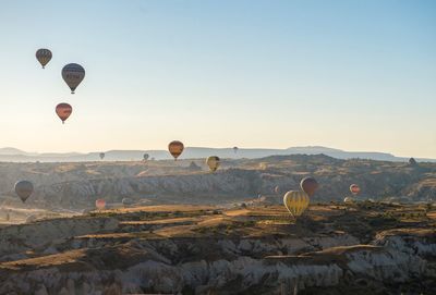 Hot air balloons flying over landscape against clear sky