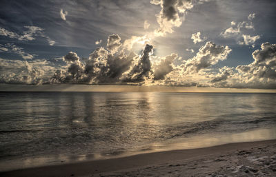 Sun peeks through the clouds over the ocean at sunset in naples, florida