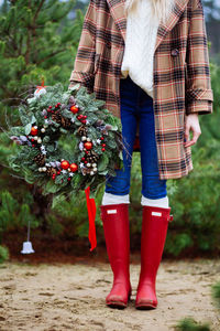 Low section of woman standing by red flowering plants