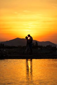 Rear view of silhouette man standing at sunset