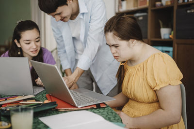 Woman with down syndrome learning through laptop by siblings at home