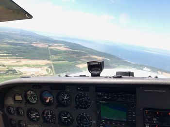 Close-up of airplane flying over landscape against sky