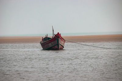 Fishing boat in sea against clear sky