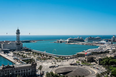 High angle view of cityscape by sea against clear sky