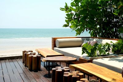 Table and chairs at beach against clear sky