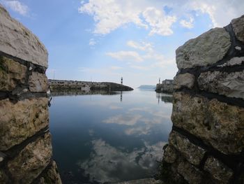 Rock formations by lake against sky