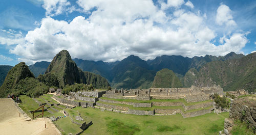 Panoramic view of green landscape against cloudy sky