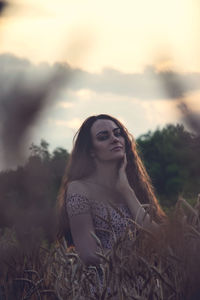 Portrait of young woman on field against sky during sunset