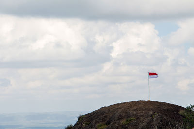 Low angle view of flag on mountain against sky