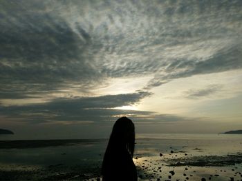 Woman on beach against sky during sunset