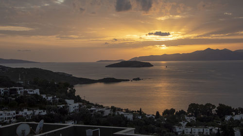 High angle view of sea and buildings against sky at sunset