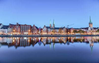Reflection of illuminated buildings in river against sky