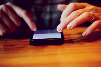 Cropped image of woman using cellphone on table