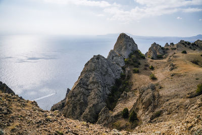 Rocks on shore by sea against sky