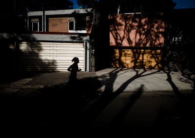 Silhouette person running on street by building