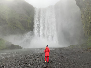 Rear view of man standing against waterfall