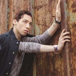 Thoughtful young man looking away while standing by rusty metal