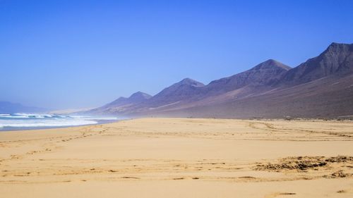 Scenic view of beach against clear blue sky