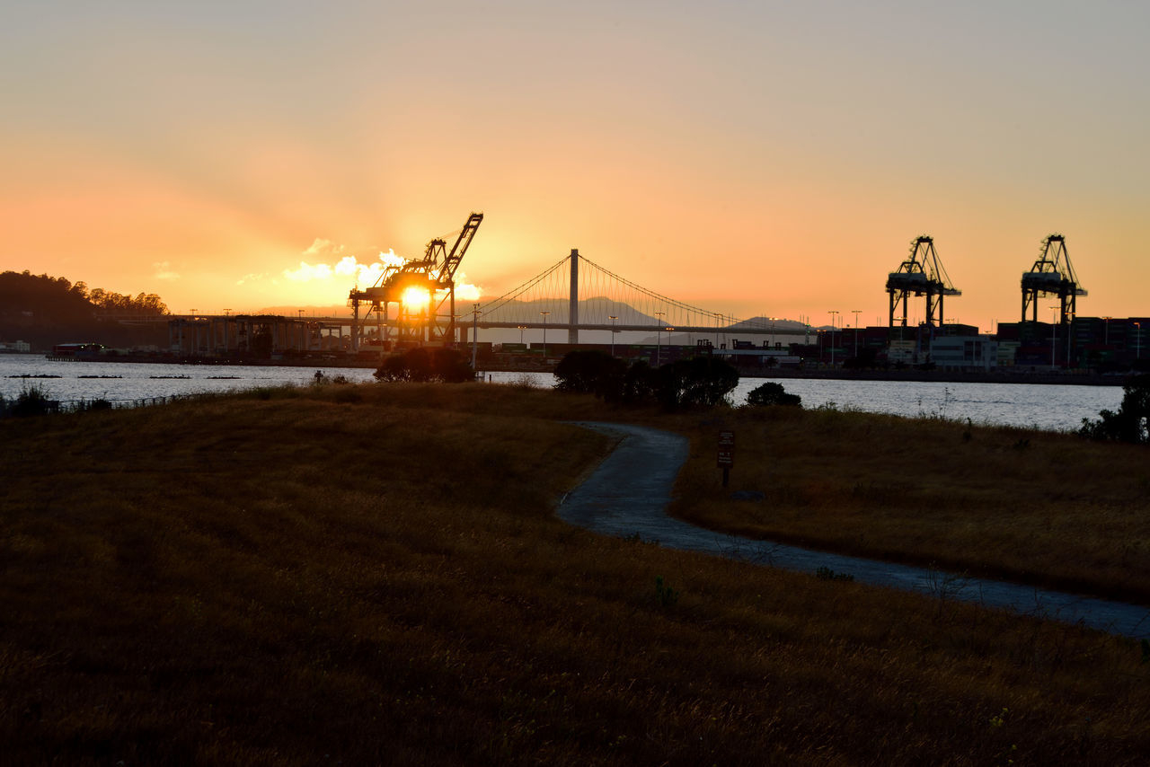 BRIDGE OVER RIVER AGAINST ORANGE SKY