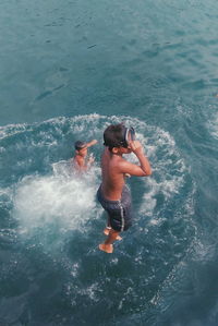 High angle view of shirtless boys playing in sea