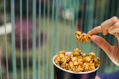 Close-up of hand holding caramel popcorn at theatre