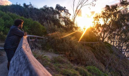 Rear view of woman on road against sky during sunset