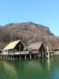 House by lake against clear blue sky