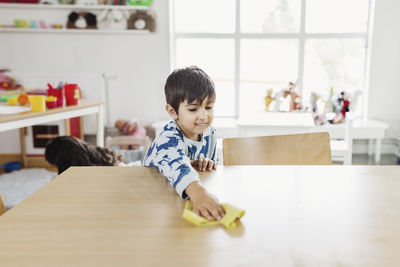 Boy cleaning dining table at day care center