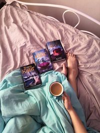 High angle view of woman with coffee cup on bed