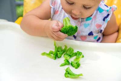 Cute baby eating broccoli