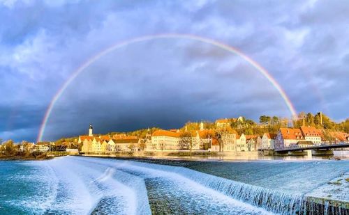 Scenic view of rainbow over river against sky