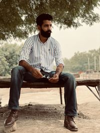 Full length of young man sitting in park