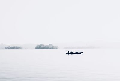 Boat sailing in lake against sky during winter