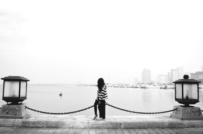 Full length of woman standing by sea against clear sky