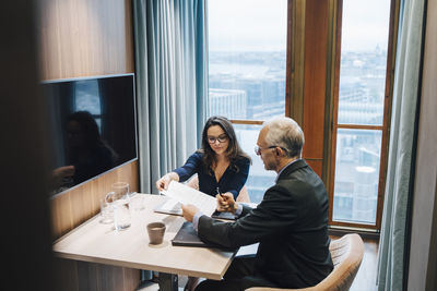 Female entrepreneur discussing with male colleague over document in board room at office