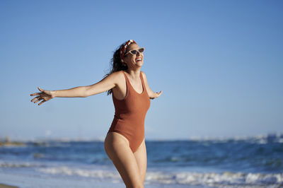 Cheerful woman with arms outstretched enjoying at beach