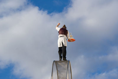 Low angle view of woman standing against sky