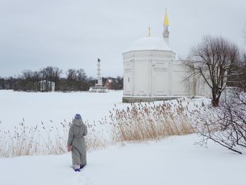 Rear view of man walking on snow covered field