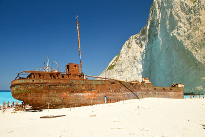 Scenic view of shipwreck on beach against clear blue sky