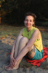 Portrait of smiling young woman sitting on land