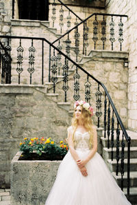 Portrait of young woman standing against building