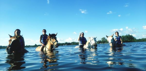 People enjoying in water against blue sky