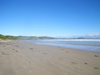 Scenic view of beach against blue sky