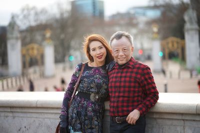 Portrait of couple woman standing by retaining wall