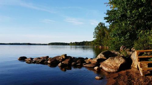 Rocks by lake against sky