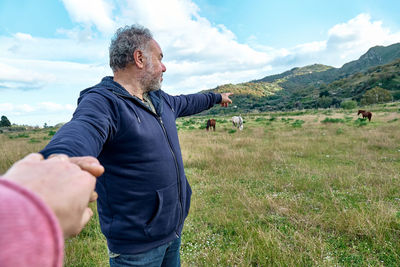 Follow me. man holds and pulls the photographer's hand while walking on the pasture